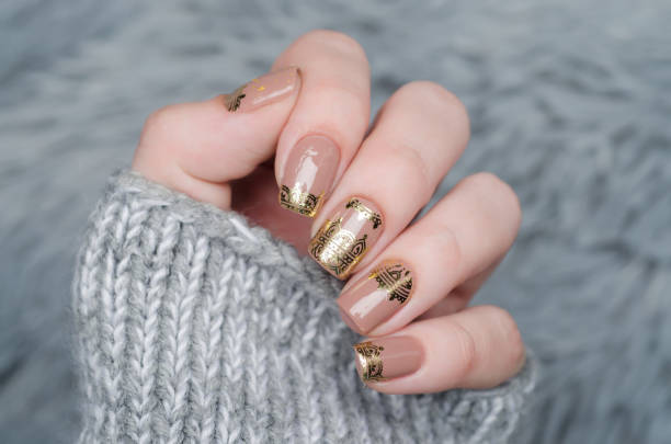 istock beige Nude manicure with gold lace pattern on a gray background 1195392514