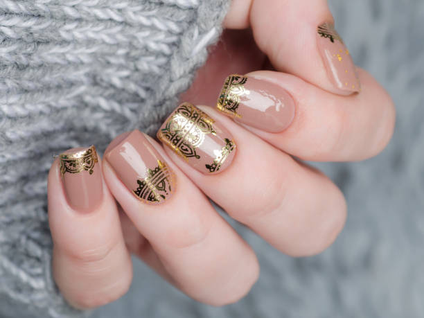 beige Nude manicure with gold lace pattern on gray background
