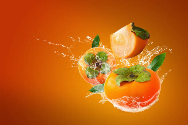 istock Water splashing on Fresh persimmons on orange background 1195392915