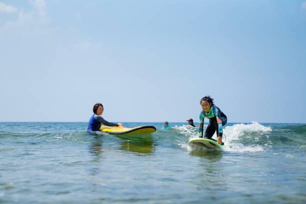 istock Mother teaching her twelve year old daughter how to surf 1195393481