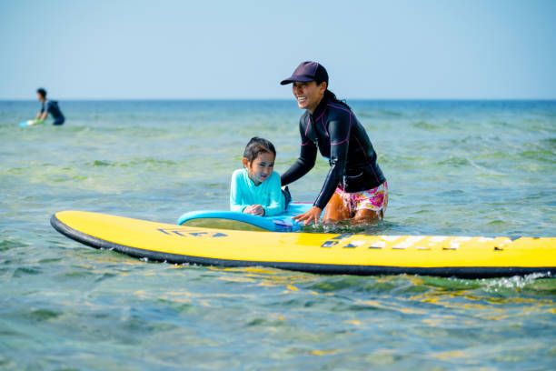 istock Mother teaching her young daughter how to surf during a tropical vacation 1195393483