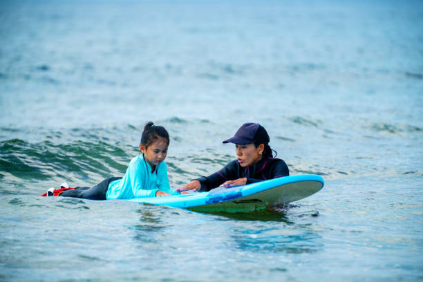 istock Young girl taking a surfing lesson 1195393523