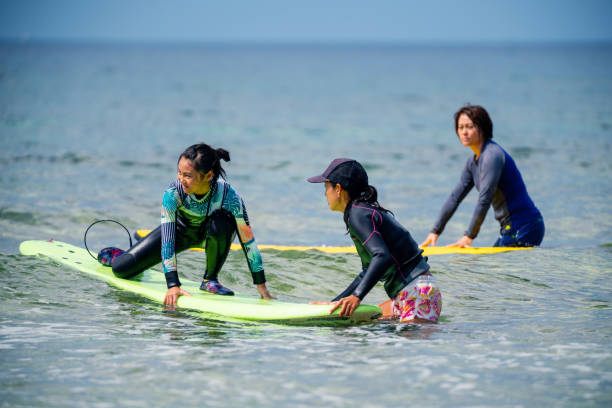 teenager-mädchen nimmt eine surf-lektion von ihrer mutter - bonding horizontal surfing surf stock-fotos und bilder