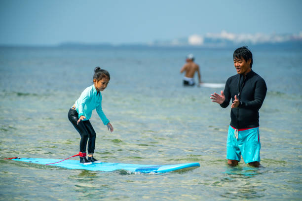 istock Father teaching his young daughter how to surf during a tropical vacation 1195393575