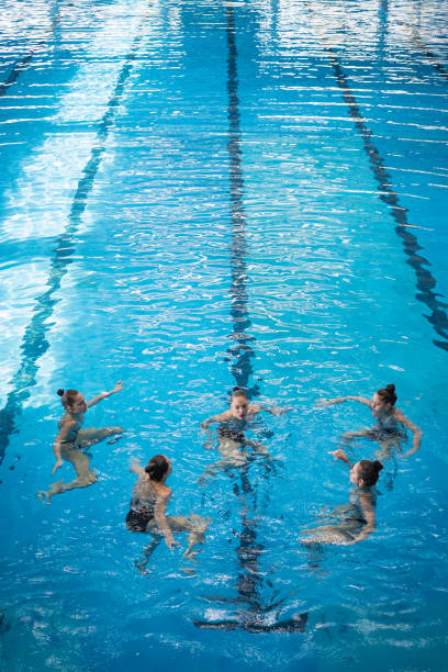 Young women exercising their performance of synchronous swimming Group of young woman exercising and performing synchronized swimming women exercising swimming pool young women stock pictures, royalty-free photos & images