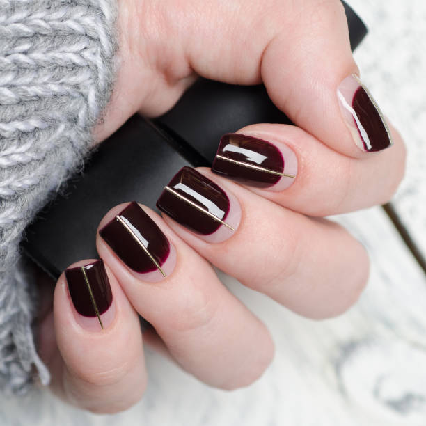 istock Burgundy manicure with negative space and Golden line on grey background 1195402456