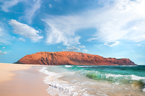 Canary islands, Spain, travel landscape. Northern side of Lanzarote, majestic cliffs, view from romantic sandy beach of Graciosa island under blue sky with clouds.