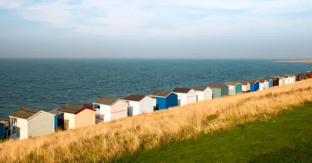 Colourful holiday wooden beach huts facing the calm atlantic ocean.  Whitstable at Kent Great Britain