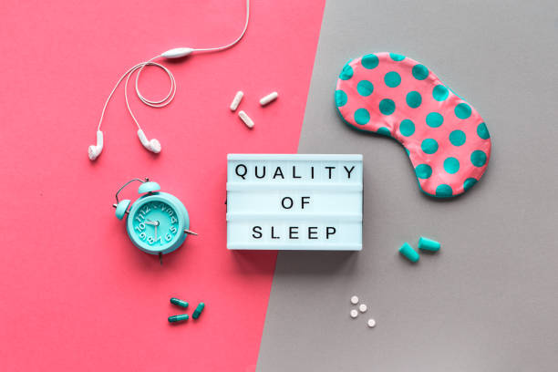 Bedtime. Little girl goes to sleep early evening with alarm clock on 9 p.m., wearing white cat, bunny sleep mask. Soft bed with white linen.Child sleep regime hours,daily routine.Sweet dreams concept.