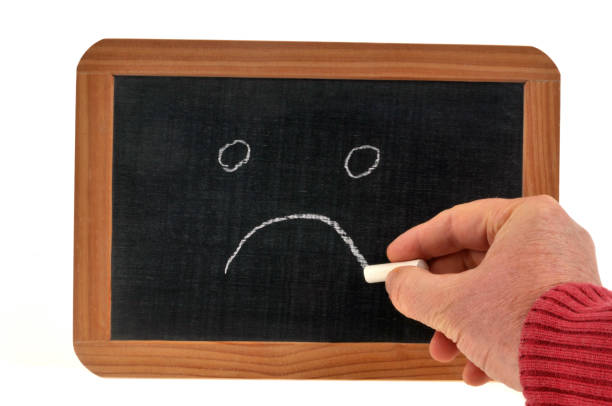 istock Sad face drawn in chalk on a school slate 1195411470