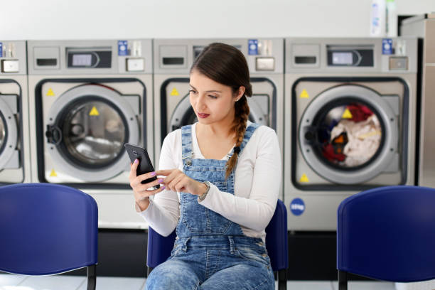 istock Woman using an app in a laundromat 1195411644