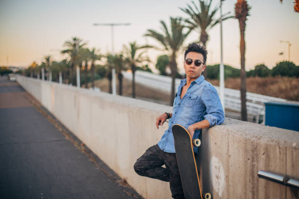 istock Handsome guy with skateboard standing on the street 1195411772