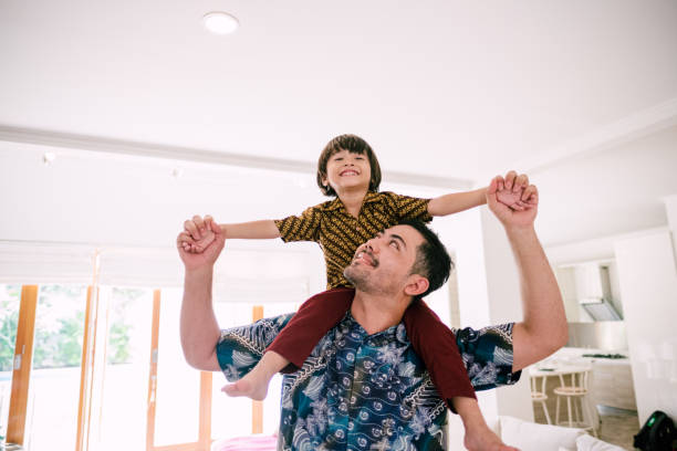 Young Asian Father Piggyback His Son Family with Batik (Traditional clothes) batik indonesia stock pictures, royalty-free photos & images