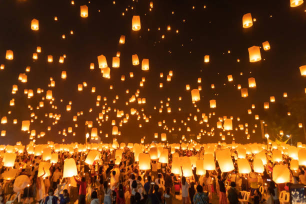 istock Thai people release sky floating lanterns or lamp to worship Buddha's relics at night. Traditional festival in Chiang mai, Thailand. Loy krathong and Yi Peng Lanna ceremony. Celebration background. 1195413944