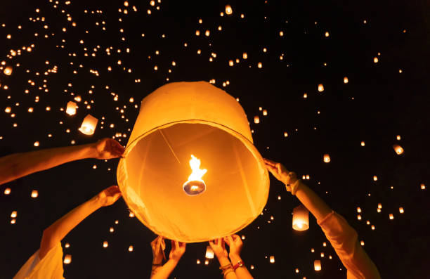 istock Thai people release sky floating lanterns or lamp to worship Buddha's relics at night. Traditional festival in Chiang mai, Thailand. Loy krathong and Yi Peng Lanna ceremony. Celebration background. 1195413965