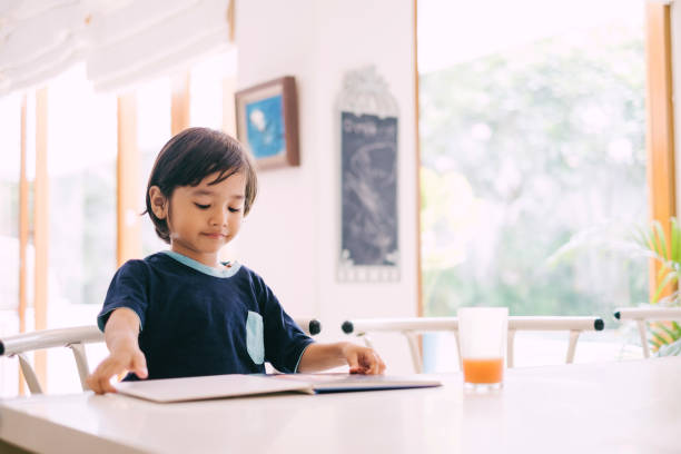 istock Happy Asian Little Boy Reading Book 1195414990