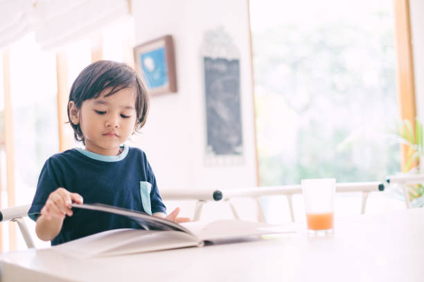 istock Happy Asian Little Boy Reading Book 1195415017