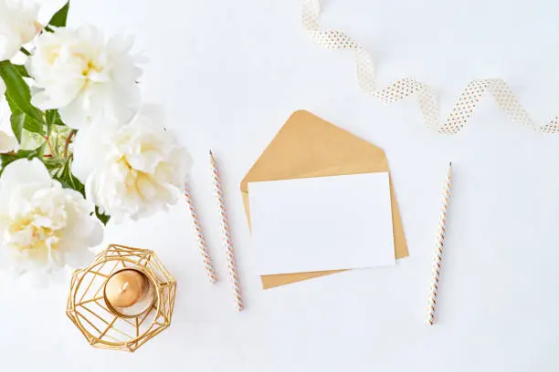 Photo of Mockup wedding invitation and envelope with white peonies on a white background