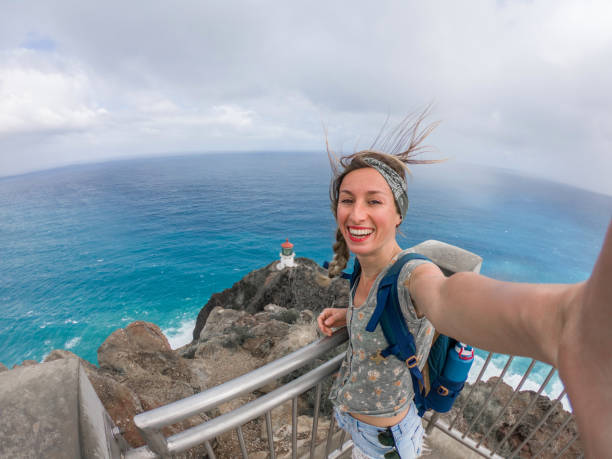 kvinna tar selfie foto på klippan med utsikt över kusten och fyr, hawaii - kustlinje videor bildbanksfoton och bilder