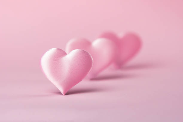 Pink silk heart on a pink background is standing in line.  The concept of minimalism.  Place for text.  Pastel colors .