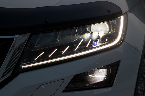 Novosibirsk, Russia - 12.19.2019: Front headlamp view of white car with  turn on led day running DRL light and bi-xenon lens