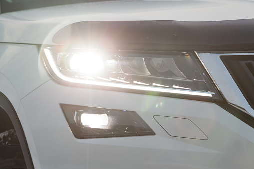 Novosibirsk, Russia - 12.19.2019: Front headlamp view of white car with  turn on led day running DRL light and bi-xenon lens