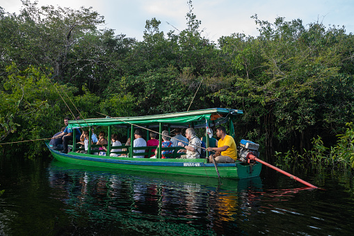 Amazon, Brazil – March 6, 2019: Amazon, Brazil - March 6, 2019: Tourists in a traditional Amazon boat fishing for piranhas.
