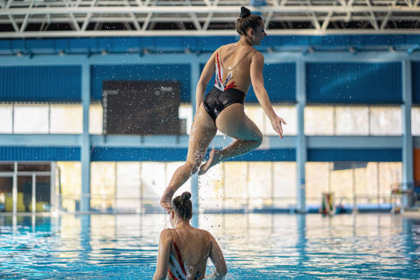 istock Young synchronized swimmer jumping out of the water during a duet performance 1195429488