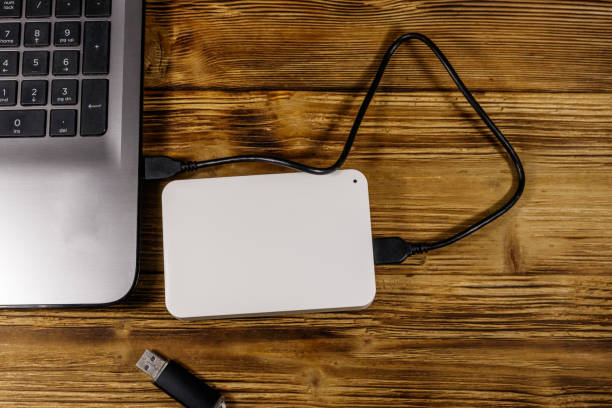 istock External HDD connected to laptop computer and USB flash drive on a wooden desk. Top view. Concept of data storage 1195431035