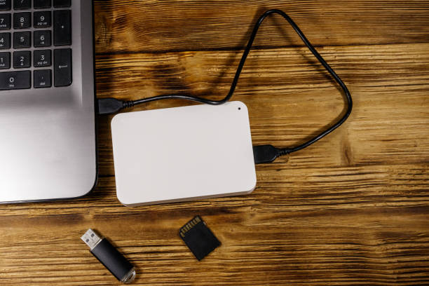 istock External HDD connected to laptop computer, SD memory card and USB flash drive on a wooden desk. Top view. Concept of data storage 1195431043