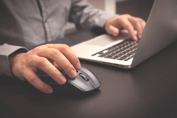 Man using a laptop and clicking a mouse