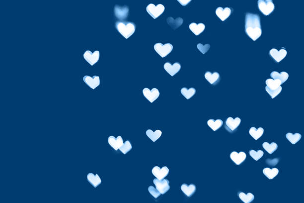 blue colored festive background with white heart bokeh