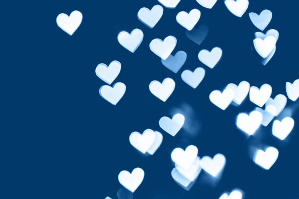 istock blue colored festive background with white heart bokeh 1195432506
