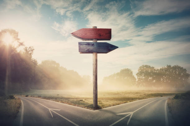 paysage surréaliste avec une route fendue et des flèches de signalisation montrant deux cours différents, direction gauche et droite à choisir. la route se divise de façon distincte. décision difficile, concept de choix. - favorite photos et images de collection