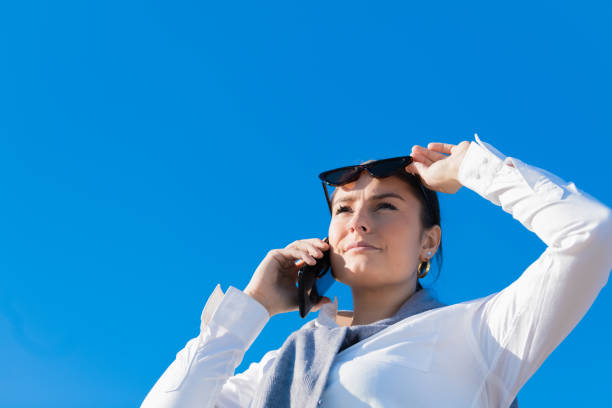 istock woman raises her sunglasses checking a blue sky 1195435509