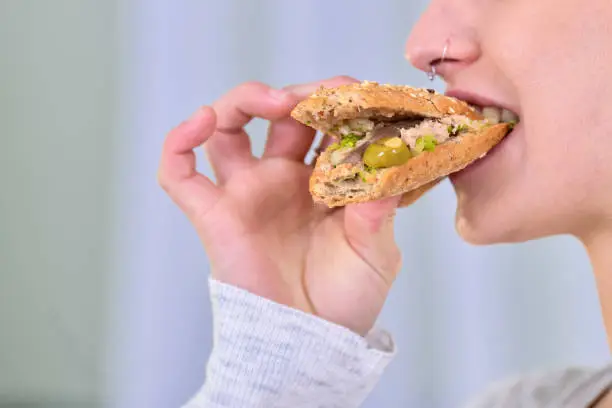 Photo of Close-up of a woman biting a tuna sandwich