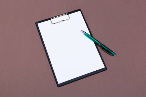 istock Clipboard with white sheet and pen on a colored background. View from above. space for text 1195436574