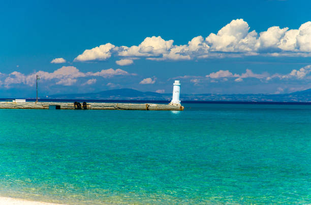 View of white pier jetty on blue paradise water of Toroneos kolpos gulf, blue sky, white clouds over Sithonia peninsula in Pefkohori, Halkidiki Kassandra, Macedonia, Greece