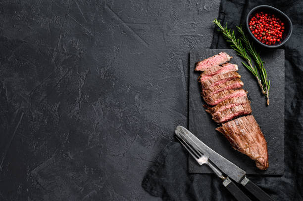 istock Sliced beef flank steak medium rare. Black background. Top view. Space for text 1195444335