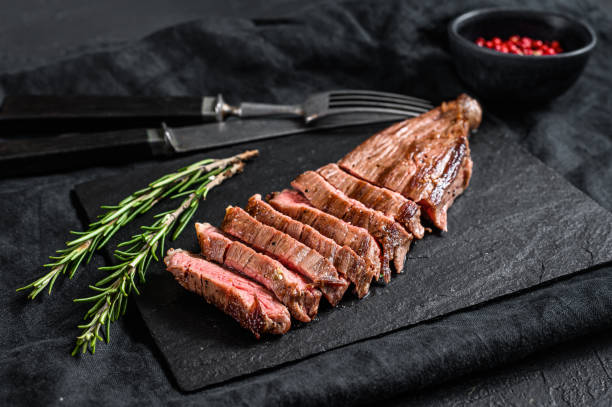 Sliced beef flank steak medium rare. Black background. Top view