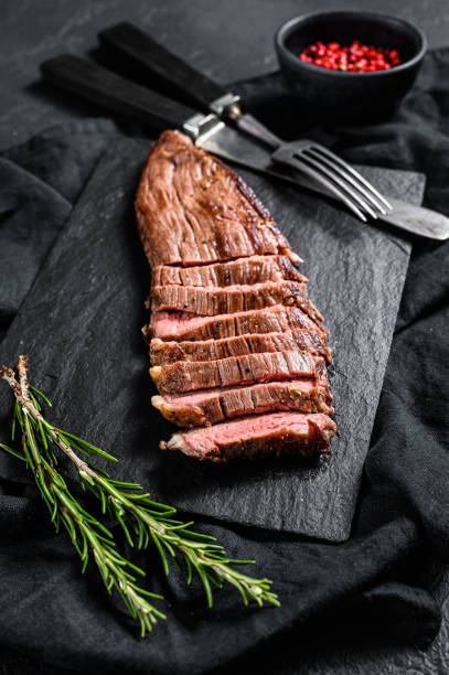 istock Sliced beef flank steak medium rare. Black background. Top view 1195444973