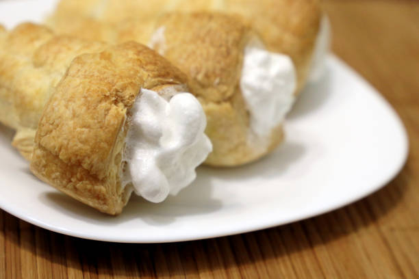 istock Rolls of puff pastry with protein cream on a white plate 1195445167