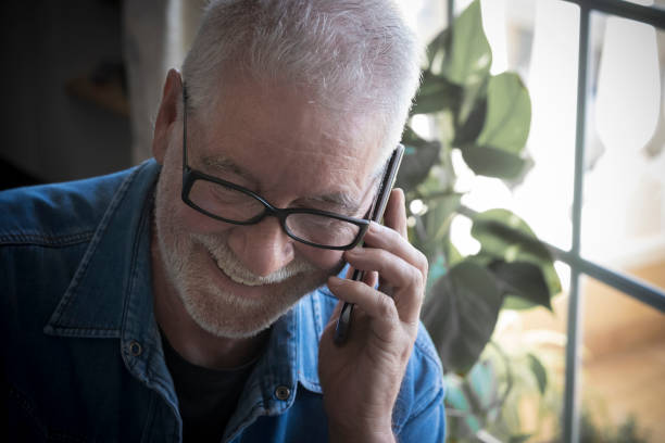 istock Attractive senior people with white beard and eyeglasses using the cellphone. Smiling listening good news. One caucasian man 1195446179