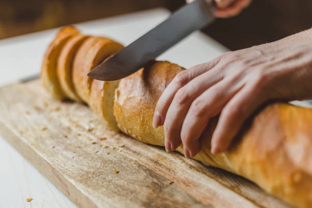 istock Fresh Crisp White Wheat Bread - Female Hands Slicing Baguette 1195446492