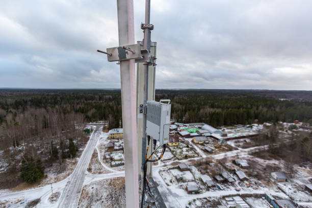istock Top of red telecommunication tower with vertical panel antenna  and  remote radio unit, power and optic cables in winter day 1195453020
