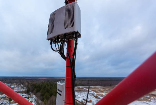 istock Top of red telecommunication tower with vertical panel antenna  and  remote radio unit, power and optic cables in winter day 1195453028