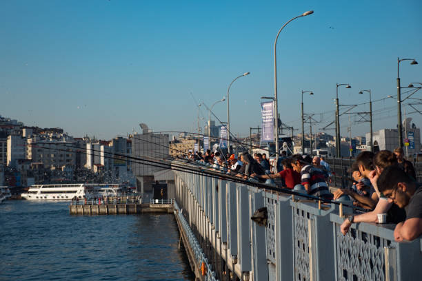 ISTANBUL, TURKEY - JULY 30 2019: Fishermen at the crowded Galata bridge with restaurants on the lower deck