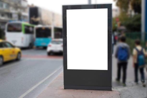 istock Blank white rectangular billboard at the roadside. On the left comes 2 teenagers on foot. 1195455486