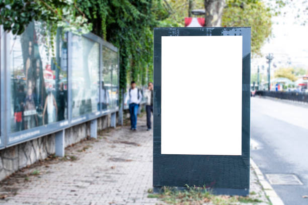istock Blank white rectangular billboard at the roadside. On the left comes 2 teenagers on foot. 1195457809
