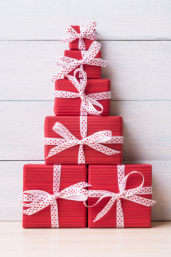 Red gift boxes in the shape of Christmas tree over white wooden background